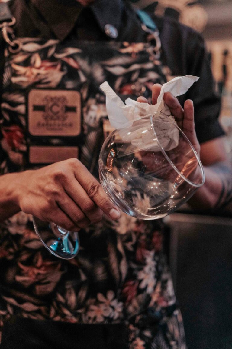 Close-up of a bartender meticulously polishing a wine glass with a cloth, creating a professional and clean presentation.